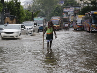 A city corporation cleaner is walking through a waterlogged street during heavy rainfall in Dhaka, Bangladesh, on June 26, 2024. (