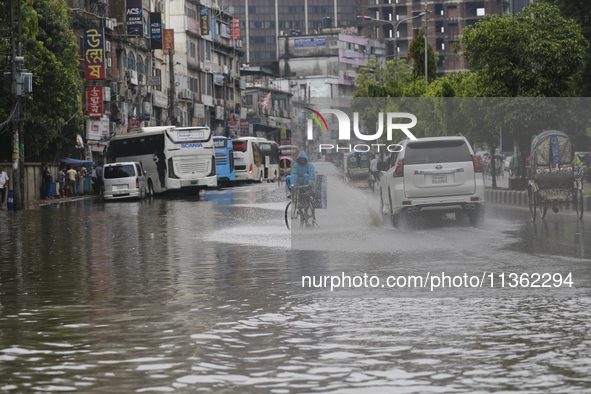 A delivery man is riding a bicycle through a waterlogged street during heavy rainfall in Dhaka, Bangladesh, on June 26, 2024. 