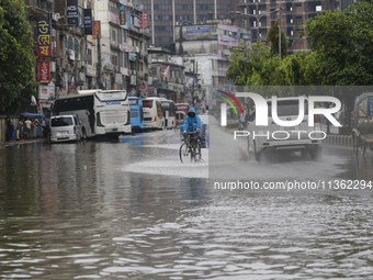 A delivery man is riding a bicycle through a waterlogged street during heavy rainfall in Dhaka, Bangladesh, on June 26, 2024. (