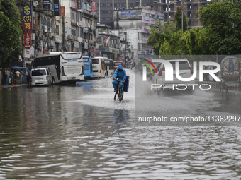 A delivery man is riding a bicycle through a waterlogged street during heavy rainfall in Dhaka, Bangladesh, on June 26, 2024. (