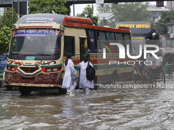 People are making their way through a waterlogged street during heavy rainfall in Dhaka, Bangladesh, on June 26, 2024. (