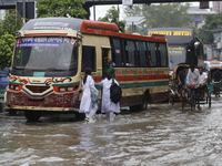 People are making their way through a waterlogged street during heavy rainfall in Dhaka, Bangladesh, on June 26, 2024. (