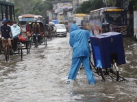 A delivery man is walking through a waterlogged street during heavy rainfall in Dhaka, Bangladesh, on June 26, 2024. (