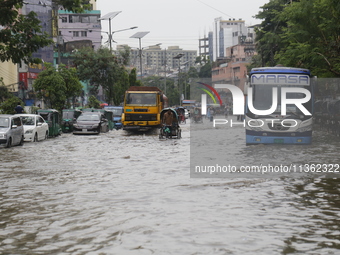 People are making their way through a waterlogged street during heavy rainfall in Dhaka, Bangladesh, on June 26, 2024. (