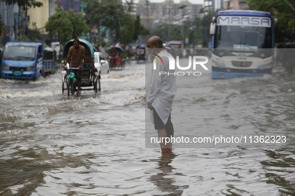 A man is walking through a waterlogged street during heavy rainfall in Dhaka, Bangladesh, on June 26, 2024. 