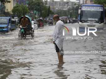 A man is walking through a waterlogged street during heavy rainfall in Dhaka, Bangladesh, on June 26, 2024. (