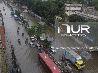 People are making their way through a waterlogged street during heavy rainfall in Dhaka, Bangladesh, on June 26, 2024. (