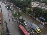 People are making their way through a waterlogged street during heavy rainfall in Dhaka, Bangladesh, on June 26, 2024. (