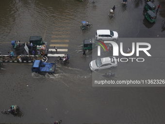 People are making their way through a waterlogged street during heavy rainfall in Dhaka, Bangladesh, on June 26, 2024. (