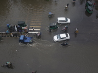 People are making their way through a waterlogged street during heavy rainfall in Dhaka, Bangladesh, on June 26, 2024. (