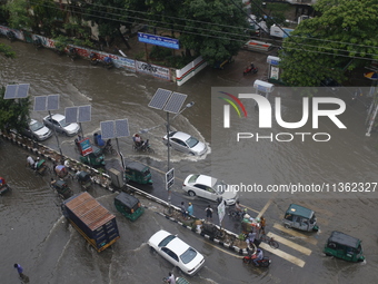 People are making their way through a waterlogged street during heavy rainfall in Dhaka, Bangladesh, on June 26, 2024. (