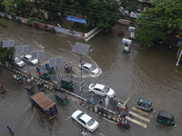 People are making their way through a waterlogged street during heavy rainfall in Dhaka, Bangladesh, on June 26, 2024. (