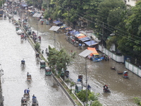 People are making their way through a waterlogged street during heavy rainfall in Dhaka, Bangladesh, on June 26, 2024. (