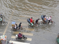 People are making their way through a waterlogged street during heavy rainfall in Dhaka, Bangladesh, on June 26, 2024. (