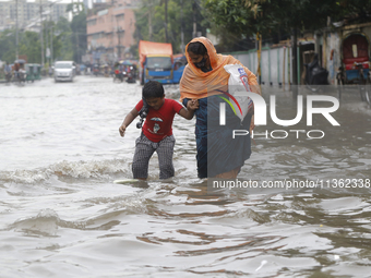 A woman is walking through a waterlogged street during heavy rainfall in Dhaka, Bangladesh, on June 26, 2024. (