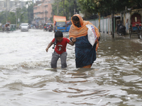 A woman is walking through a waterlogged street during heavy rainfall in Dhaka, Bangladesh, on June 26, 2024. (