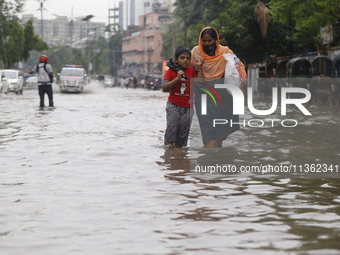 A woman is walking through a waterlogged street during heavy rainfall in Dhaka, Bangladesh, on June 26, 2024. (