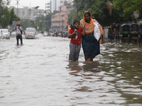 A woman is walking through a waterlogged street during heavy rainfall in Dhaka, Bangladesh, on June 26, 2024. (