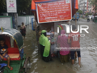 Lower-income people are buying government-subsidized food from vehicles as a street is flooding after heavy rainfall in Dhaka, Bangladesh, o...