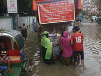 Lower-income people are buying government-subsidized food from vehicles as a street is flooding after heavy rainfall in Dhaka, Bangladesh, o...