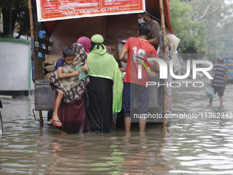 Lower-income people are buying government-subsidized food from vehicles as a street is flooding after heavy rainfall in Dhaka, Bangladesh, o...