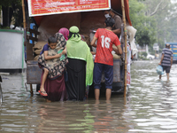 Lower-income people are buying government-subsidized food from vehicles as a street is flooding after heavy rainfall in Dhaka, Bangladesh, o...