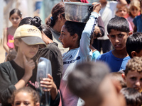 Displaced Palestinian children are waiting for food being distributed at a camp for internally displaced people where they are living due to...