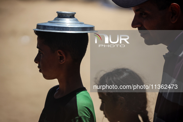 Displaced Palestinian children are waiting for food being distributed at a camp for internally displaced people where they are living due to...