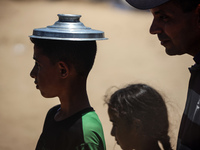 Displaced Palestinian children are waiting for food being distributed at a camp for internally displaced people where they are living due to...