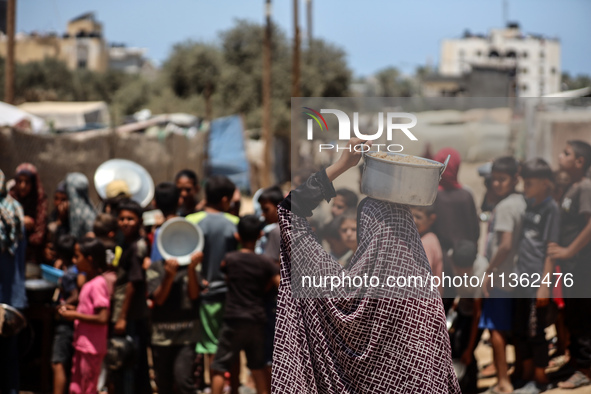 Displaced Palestinian children are waiting for food being distributed at a camp for internally displaced people where they are living due to...