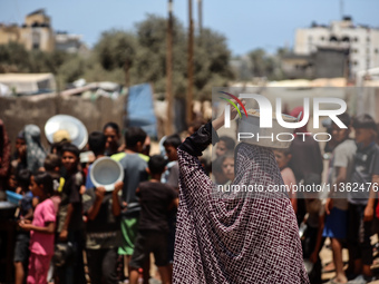 Displaced Palestinian children are waiting for food being distributed at a camp for internally displaced people where they are living due to...