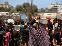 Displaced Palestinian children are waiting for food being distributed at a camp for internally displaced people where they are living due to...