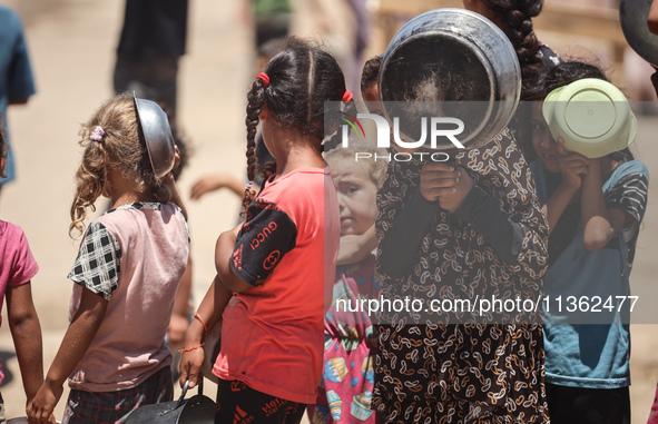 Displaced Palestinian children are waiting for food being distributed at a camp for internally displaced people where they are living due to...