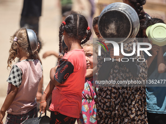 Displaced Palestinian children are waiting for food being distributed at a camp for internally displaced people where they are living due to...