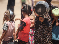 Displaced Palestinian children are waiting for food being distributed at a camp for internally displaced people where they are living due to...