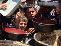 Displaced Palestinian children are waiting for food being distributed at a camp for internally displaced people where they are living due to...