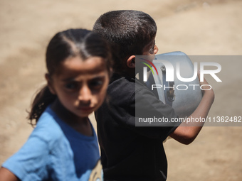 Displaced Palestinian children are waiting for food being distributed at a camp for internally displaced people where they are living due to...