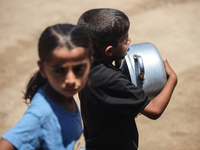 Displaced Palestinian children are waiting for food being distributed at a camp for internally displaced people where they are living due to...