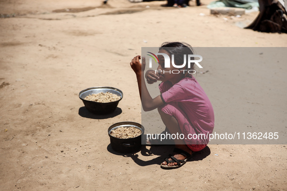 Displaced Palestinian children are receiving food at a camp for internally displaced people where they are living due to the Israeli bombard...