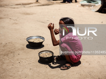 Displaced Palestinian children are receiving food at a camp for internally displaced people where they are living due to the Israeli bombard...