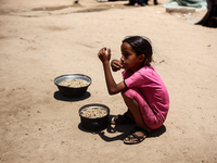 Displaced Palestinian children are receiving food at a camp for internally displaced people where they are living due to the Israeli bombard...