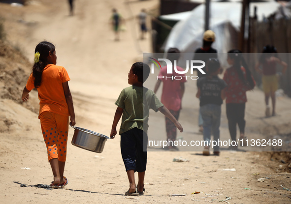 Displaced Palestinian children are receiving food at a camp for internally displaced people where they are living due to the Israeli bombard...