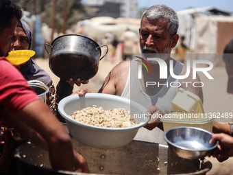 Displaced Palestinian children are waiting for food being distributed at a camp for internally displaced people where they are living due to...