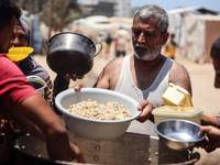 Displaced Palestinian children are waiting for food being distributed at a camp for internally displaced people where they are living due to...