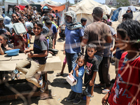 Displaced Palestinian children are waiting for food being distributed at a camp for internally displaced people where they are living due to...