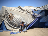 A displaced Palestinian boy is sitting in front of his tent in Deir el-Balah, on June 26, 2024, amid the ongoing conflict between Israel and...