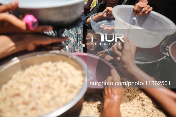 Displaced Palestinian children are waiting for food being distributed at a camp for internally displaced people where they are living due to...