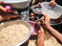 Displaced Palestinian children are waiting for food being distributed at a camp for internally displaced people where they are living due to...