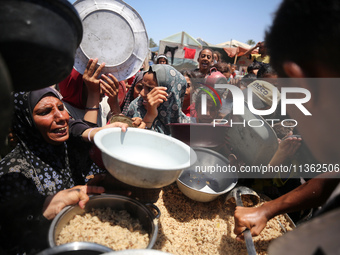 Displaced Palestinian children are waiting for food being distributed at a camp for internally displaced people where they are living due to...