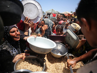 Displaced Palestinian children are waiting for food being distributed at a camp for internally displaced people where they are living due to...